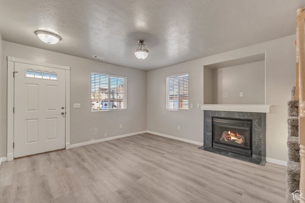 Entryway with light wood-style flooring, baseboards, visible vents, and a high end fireplace