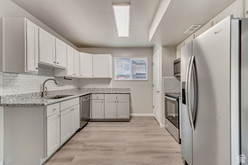 Kitchen featuring visible vents, backsplash, light stone countertops, appliances with stainless steel finishes, and a sink