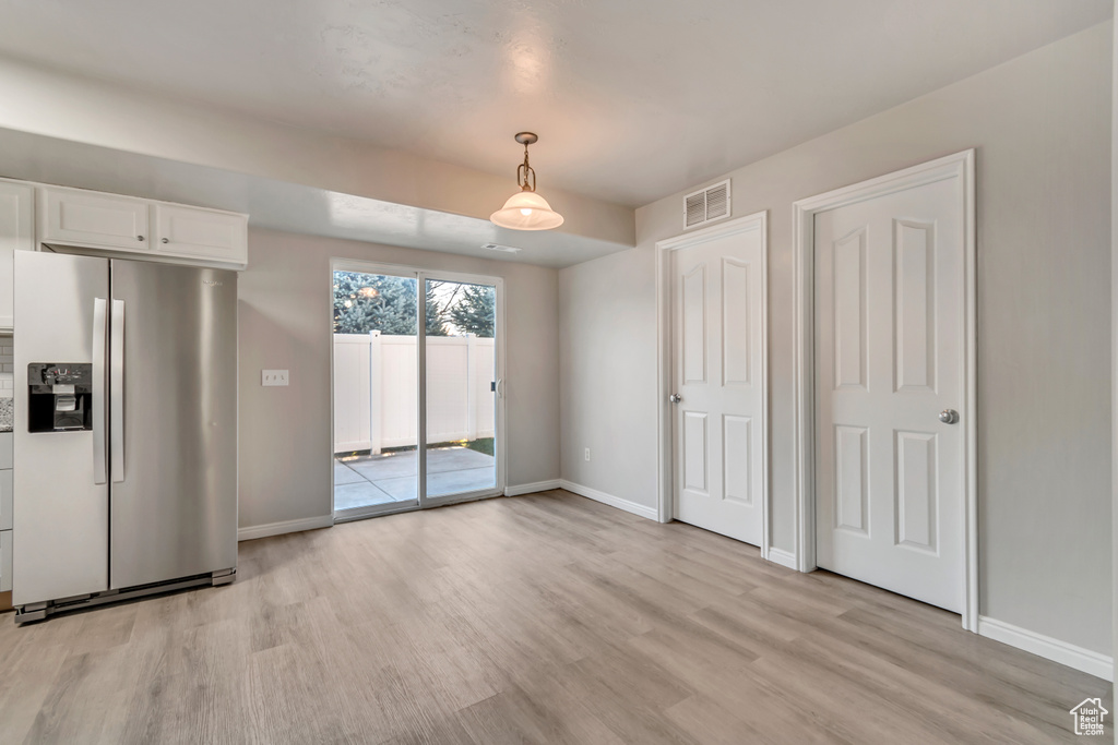 Unfurnished dining area featuring light wood-type flooring, baseboards, and visible vents