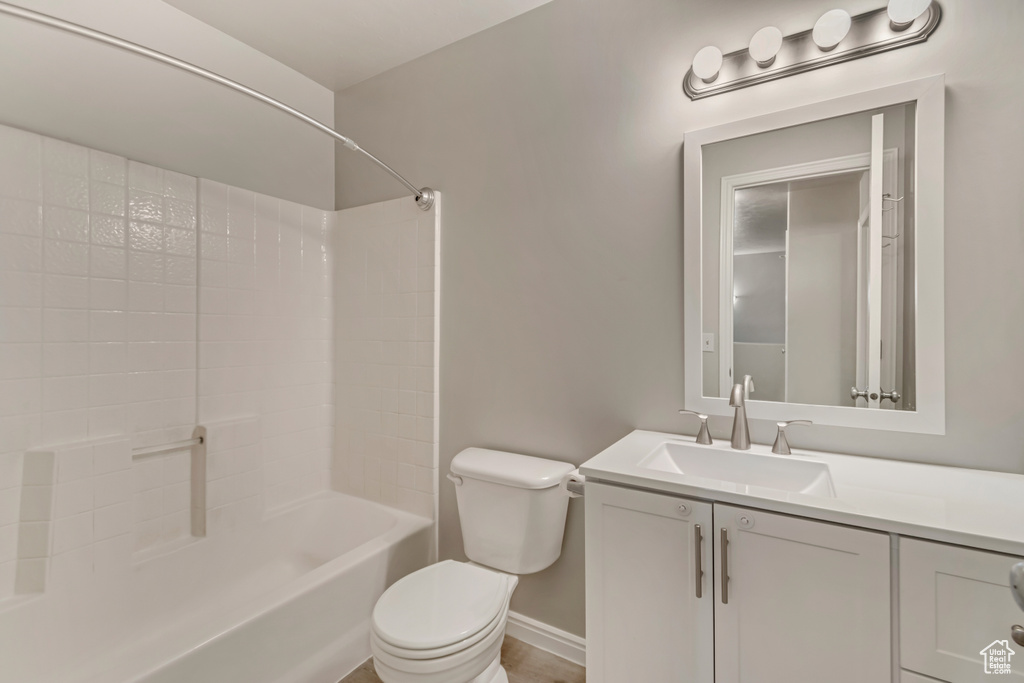 Bathroom with baseboards, toilet, vanity, and bathing tub / shower combination