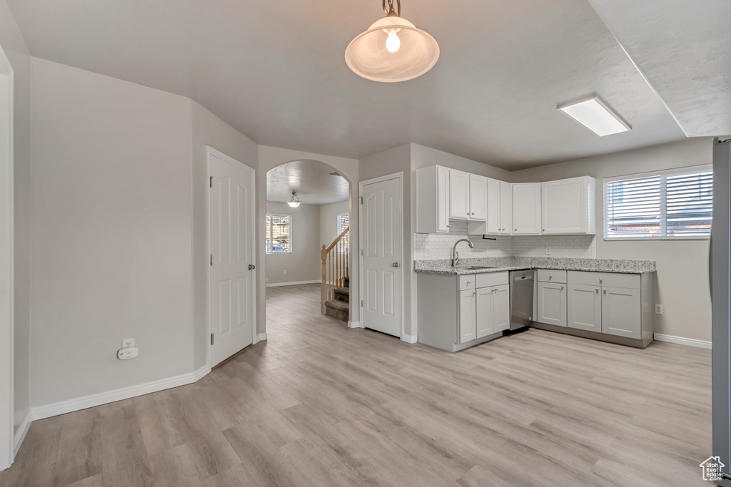 Kitchen with light stone counters, plenty of natural light, arched walkways, a sink, and backsplash