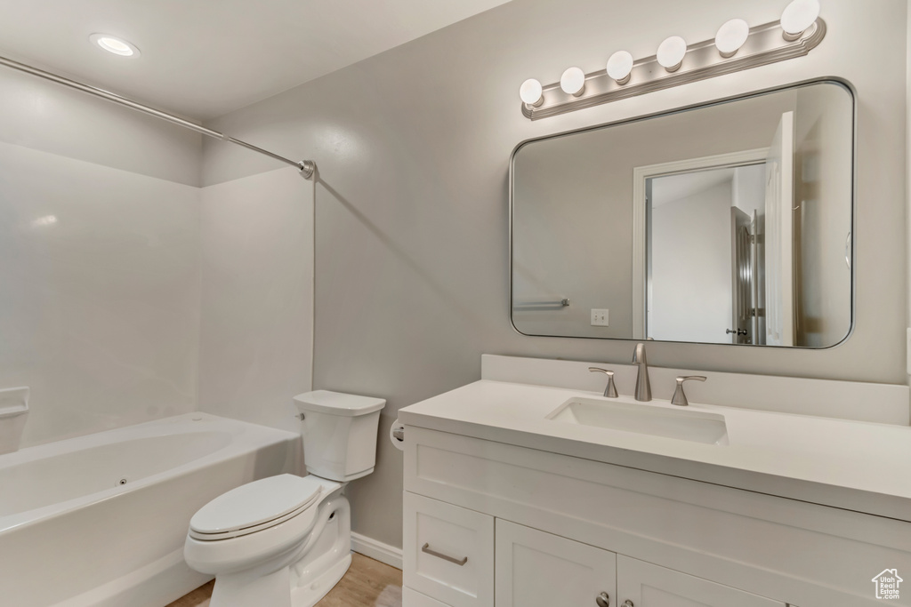 Bathroom with vanity, toilet, wood finished floors, and shower / bathtub combination