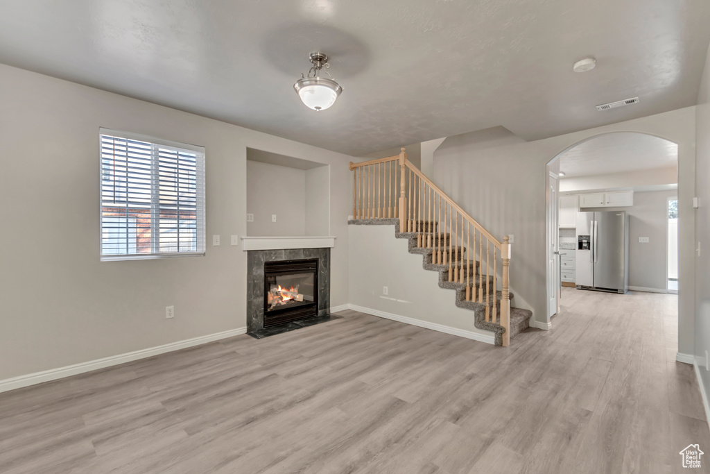 Unfurnished living room featuring visible vents, baseboards, and light wood finished floors