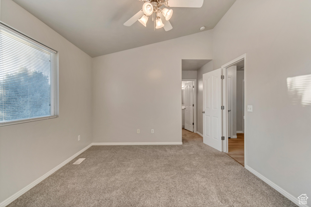 Unfurnished room with visible vents, lofted ceiling, a ceiling fan, carpet flooring, and baseboards