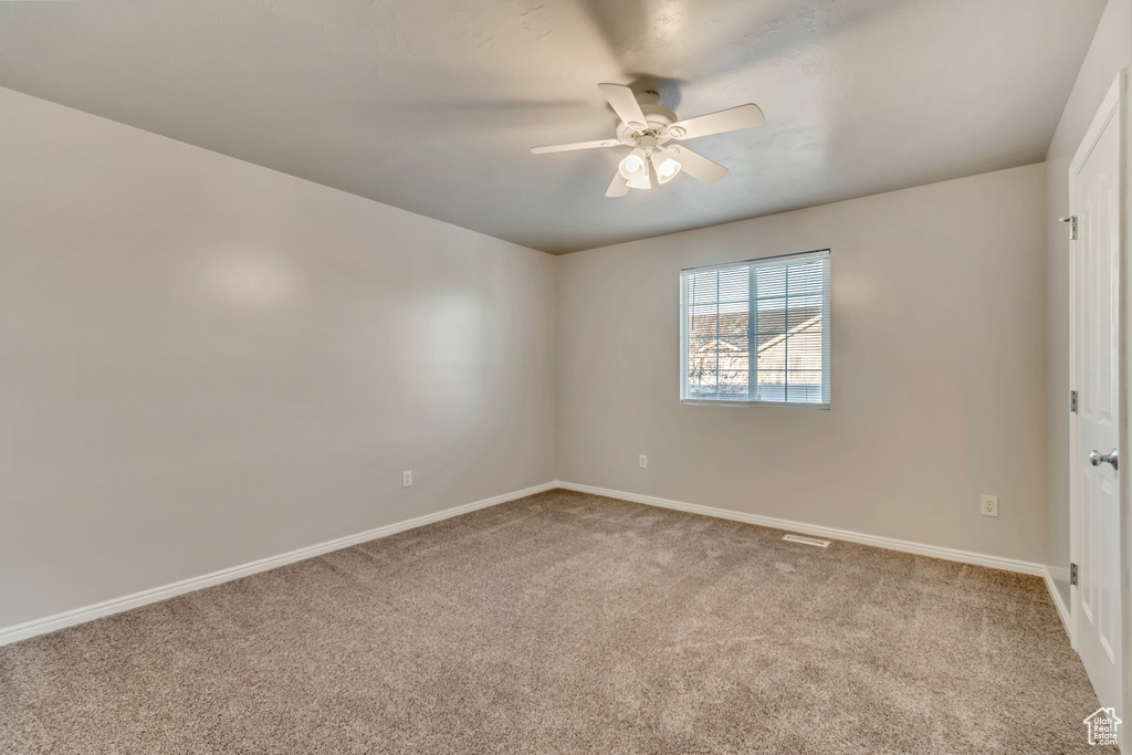 Unfurnished room featuring carpet flooring, baseboards, and ceiling fan