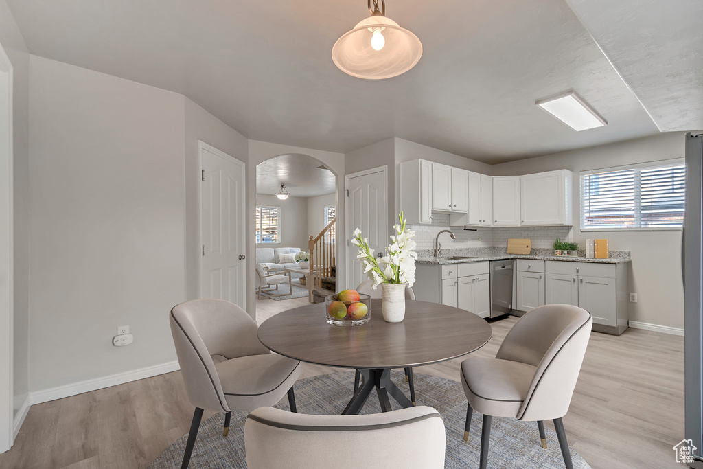 Dining room featuring stairs, light wood-style flooring, baseboards, and arched walkways