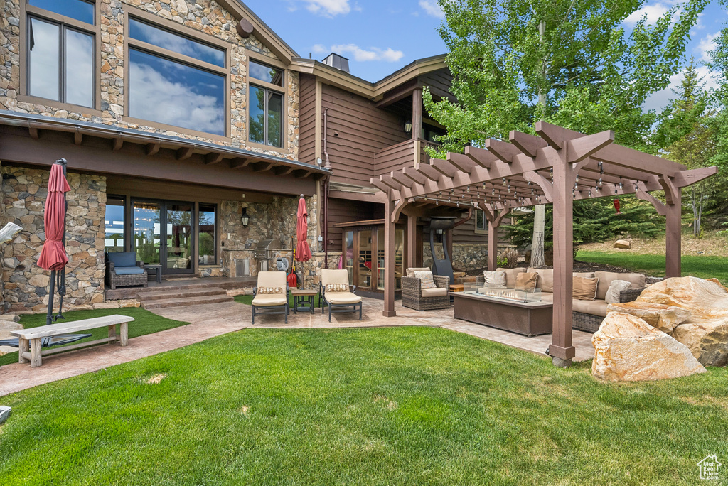 Back of property with stone siding, an outdoor living space, a pergola, a yard, and a patio
