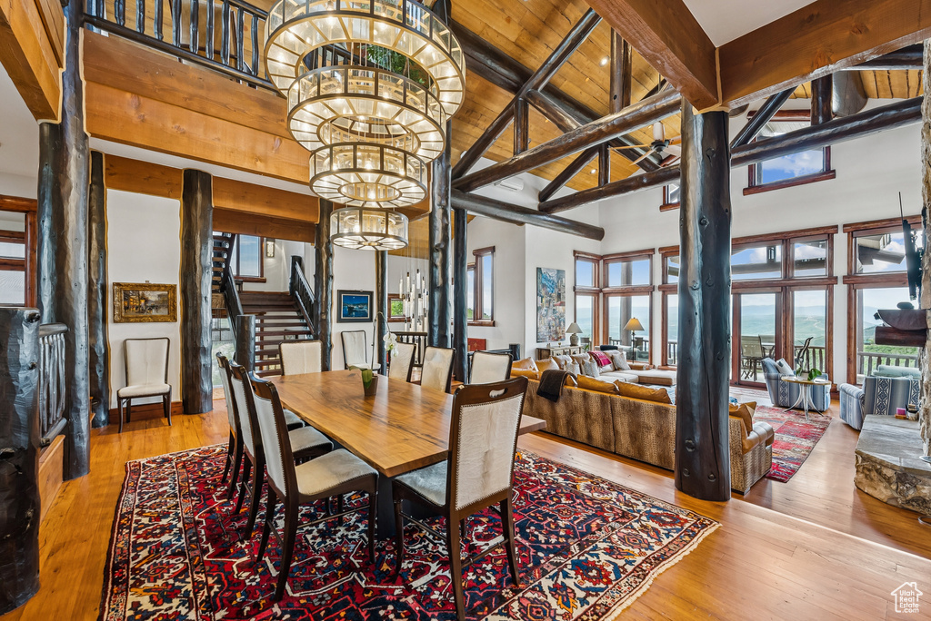 Dining room with a chandelier, stairs, hardwood / wood-style flooring, a towering ceiling, and a wood ceiling with exposed beams