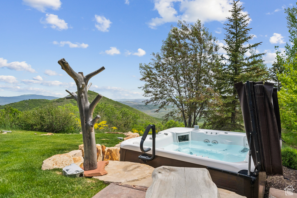 View of green lawn featuring a mountain view and a hot tub
