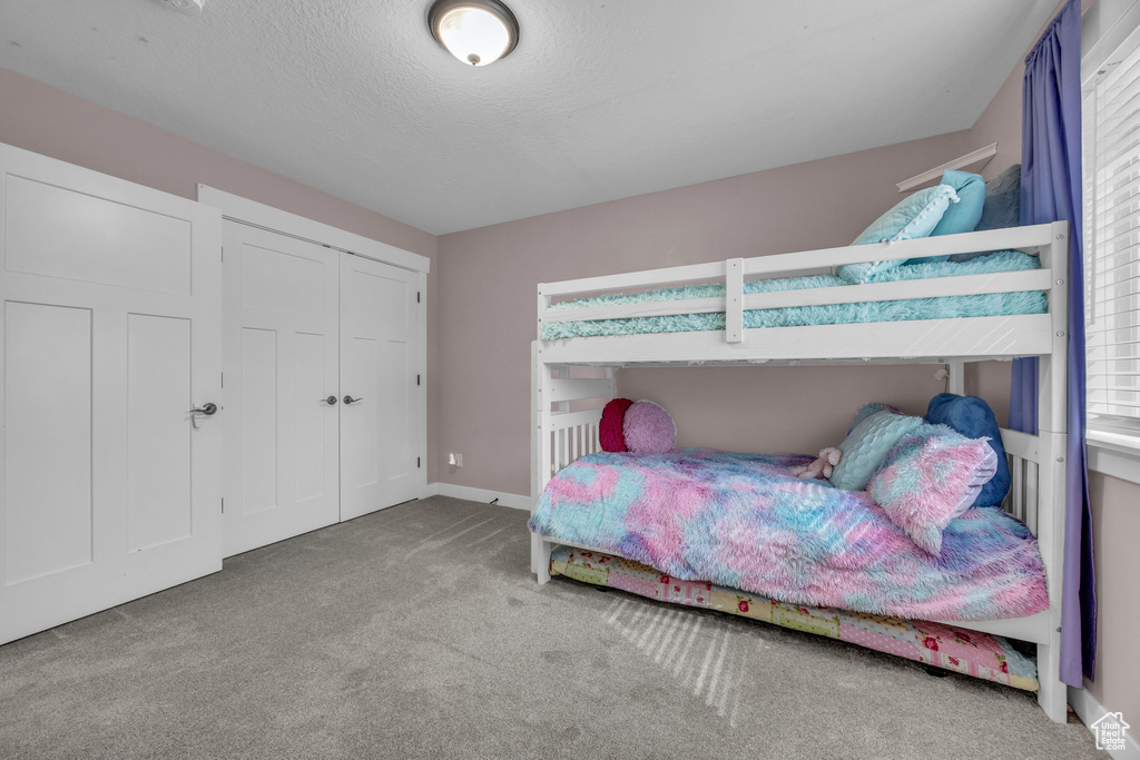 Bedroom with a closet, baseboards, carpet, and a textured ceiling