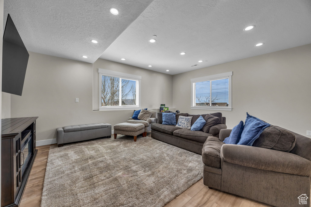 Living room with recessed lighting, plenty of natural light, a textured ceiling, and light wood finished floors