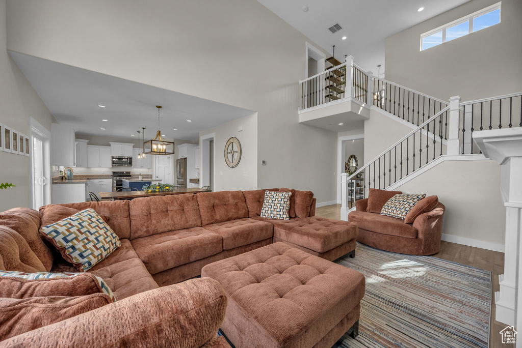 Living area with baseboards, stairway, recessed lighting, an inviting chandelier, and wood finished floors