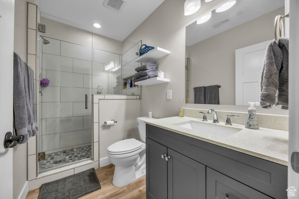 Full bath with vanity, wood finished floors, visible vents, a shower stall, and toilet