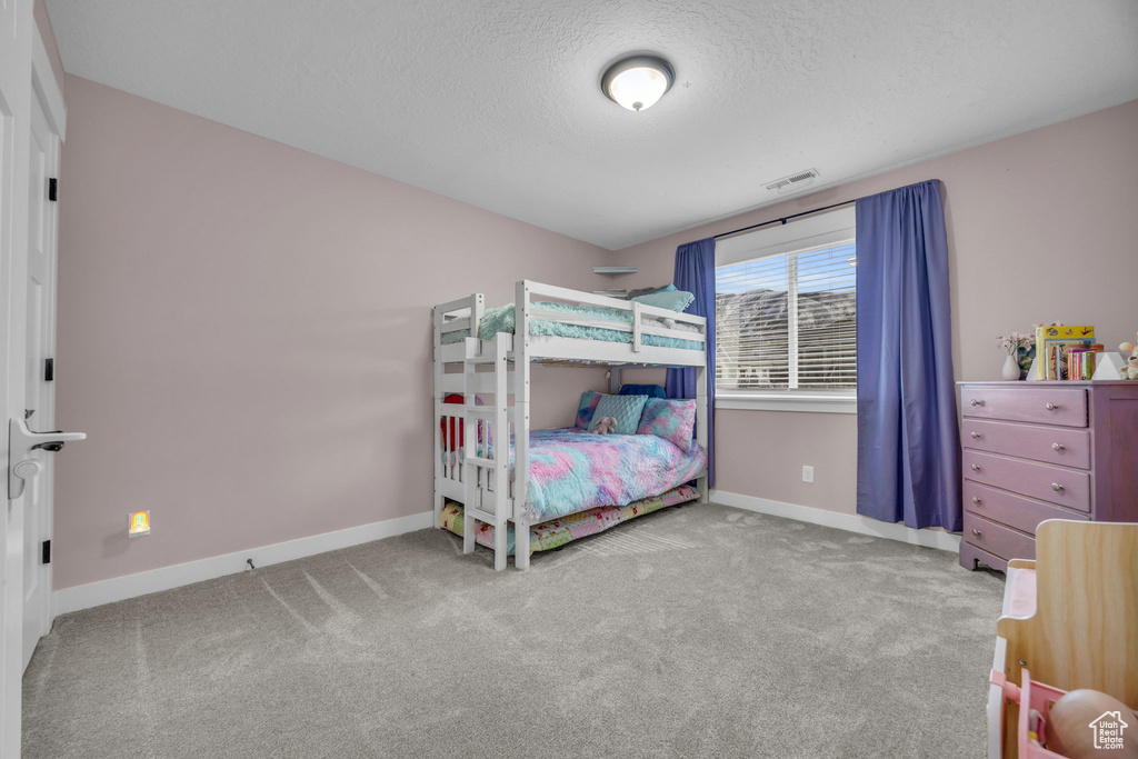 Carpeted bedroom with visible vents, a textured ceiling, and baseboards