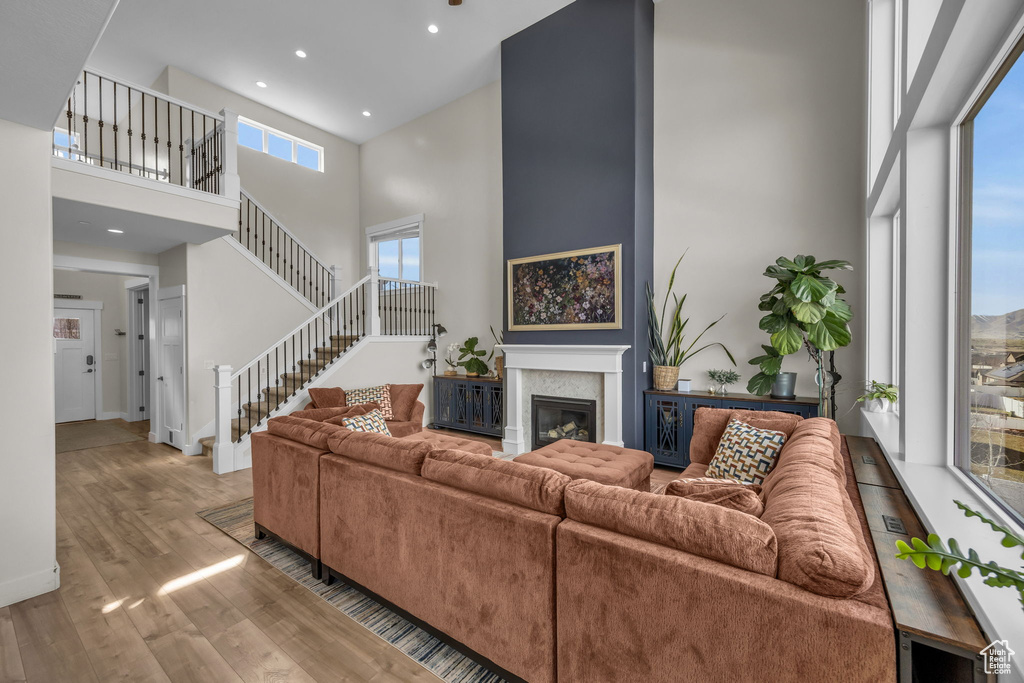 Living area featuring a glass covered fireplace, wood finished floors, stairway, a high ceiling, and baseboards