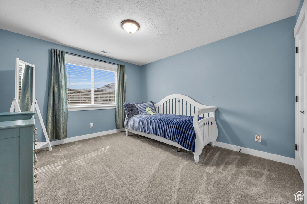 Bedroom with carpet flooring, visible vents, baseboards, and a textured ceiling