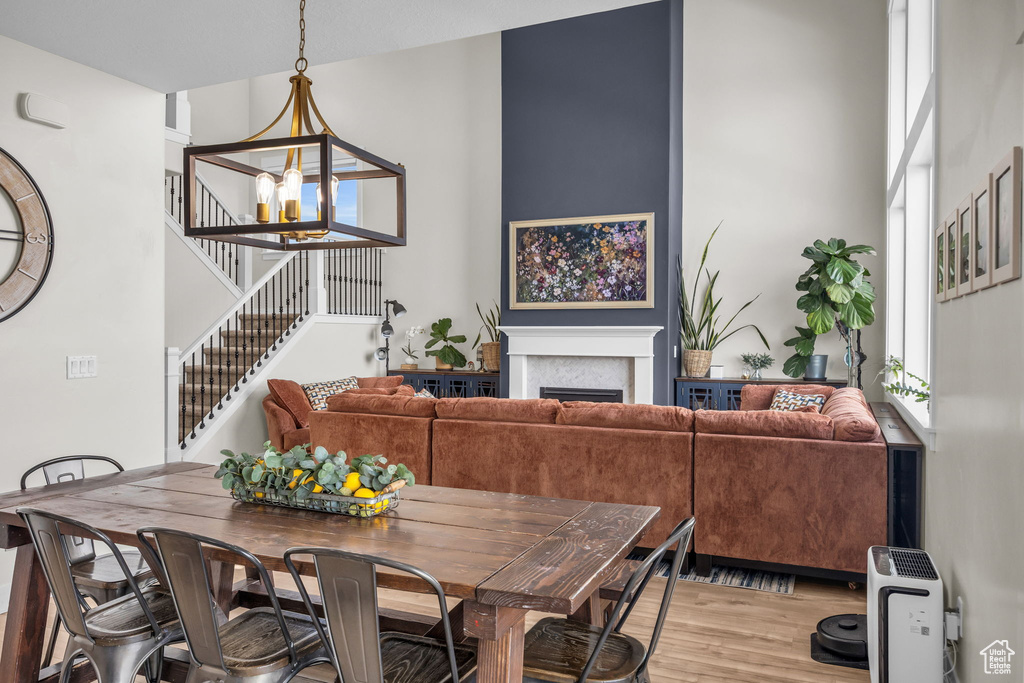 Dining area featuring an inviting chandelier, stairway, a fireplace, and light wood-style flooring