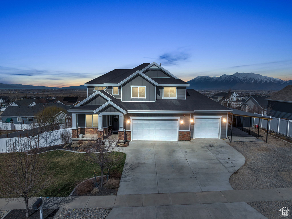 View of front facade featuring fence, a mountain view, board and batten siding, concrete driveway, and a garage