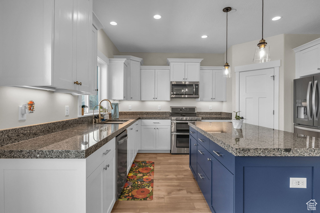 Kitchen with a sink, stainless steel appliances, blue cabinetry, and white cabinetry