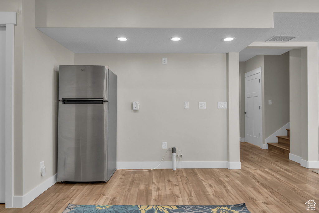 Kitchen with visible vents, baseboards, light wood-style flooring, and freestanding refrigerator