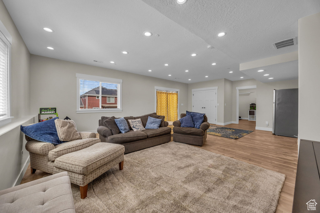 Living room with recessed lighting, visible vents, light wood-style flooring, and baseboards