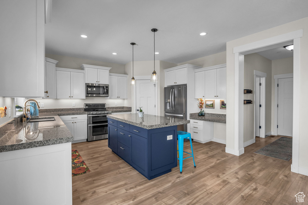 Kitchen featuring a center island, stainless steel appliances, white cabinetry, blue cabinets, and a sink