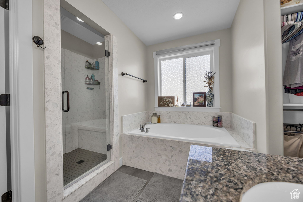 Full bathroom featuring tile patterned flooring, a shower stall, a garden tub, and a sink