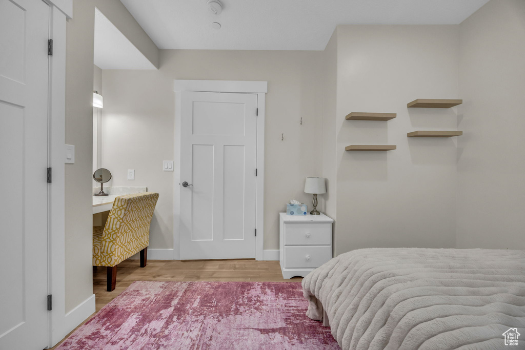 Bedroom with wood finished floors, baseboards, and built in desk