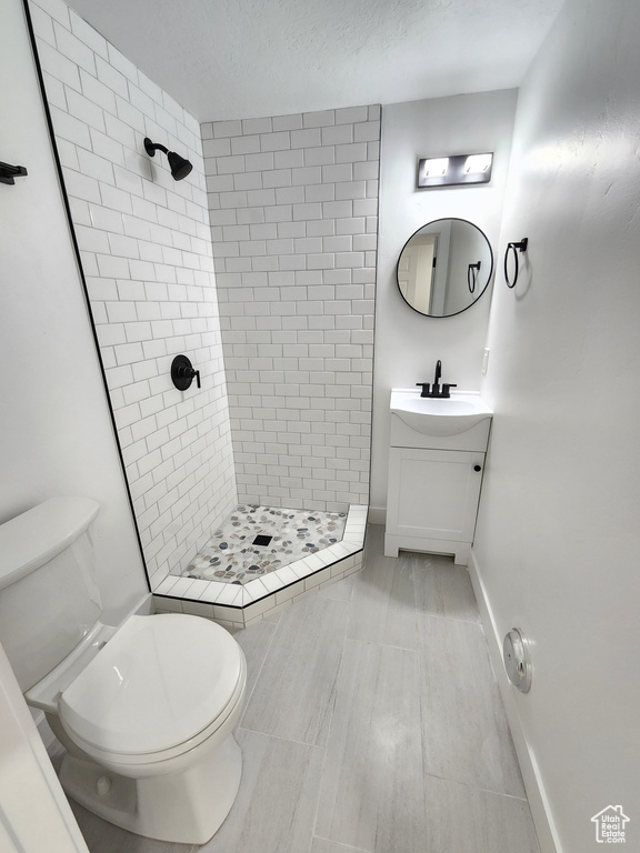 Full bathroom with vanity, a shower stall, toilet, and baseboards