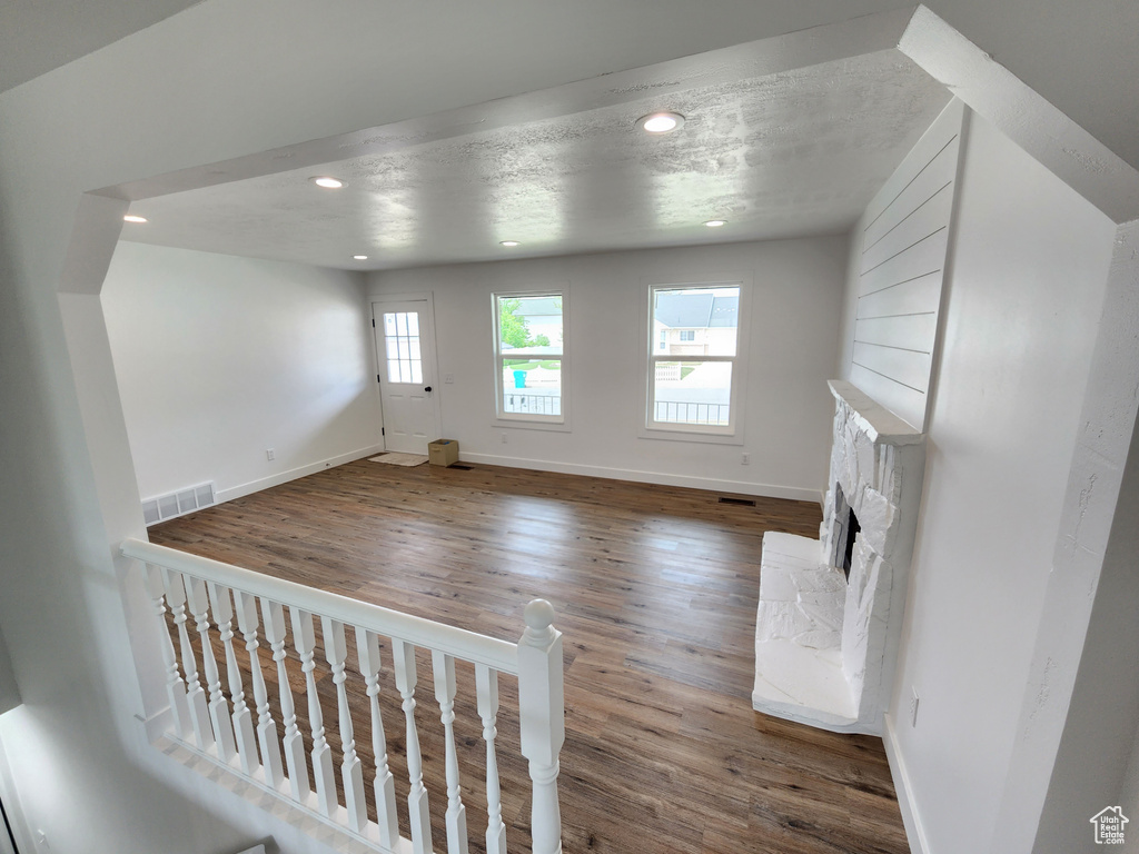 Unfurnished living room featuring a stone fireplace, recessed lighting, wood finished floors, and baseboards