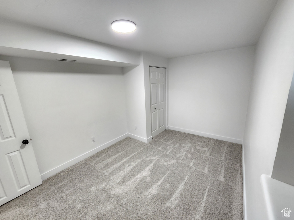 Finished basement with visible vents, baseboards, and carpet flooring
