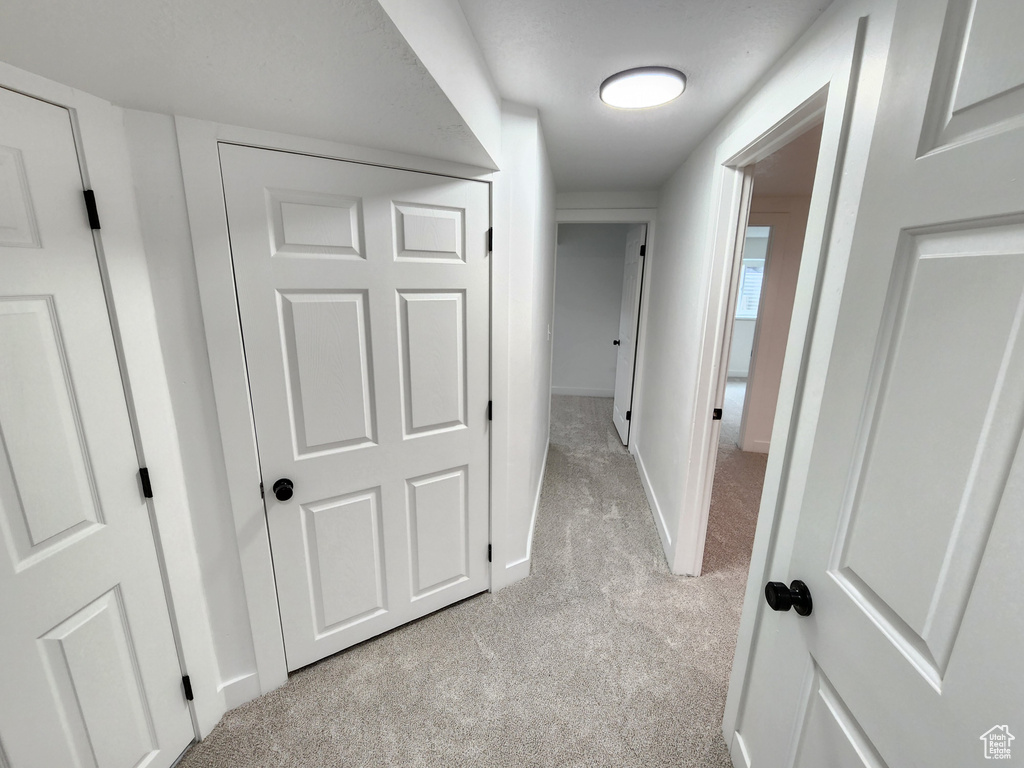 Corridor featuring light colored carpet and baseboards