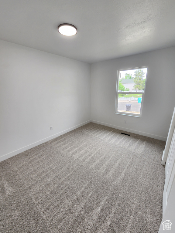 Spare room featuring visible vents, baseboards, and carpet flooring