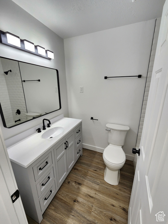 Full bathroom with vanity, toilet, wood finished floors, and walk in shower