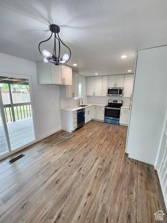 Kitchen featuring visible vents, appliances with stainless steel finishes, light wood-style floors, and a sink
