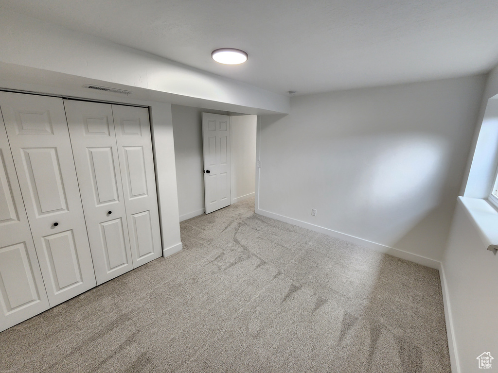 Unfurnished bedroom with visible vents, carpet floors, baseboards, and a closet