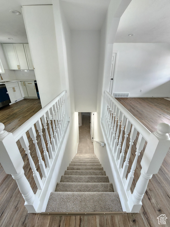 Stairway featuring visible vents and wood finished floors