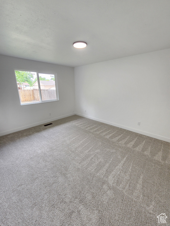 Empty room featuring visible vents, baseboards, carpet, and a textured ceiling