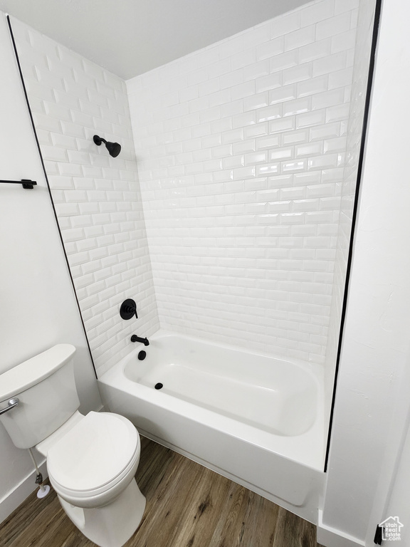 Full bath with shower / washtub combination, toilet, baseboards, and wood finished floors