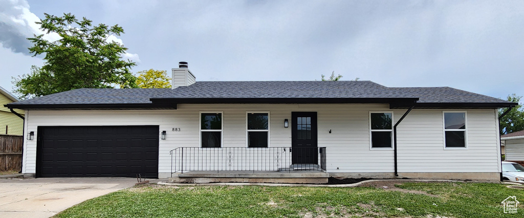 Ranch-style house featuring a front lawn, covered porch, a chimney, driveway, and an attached garage