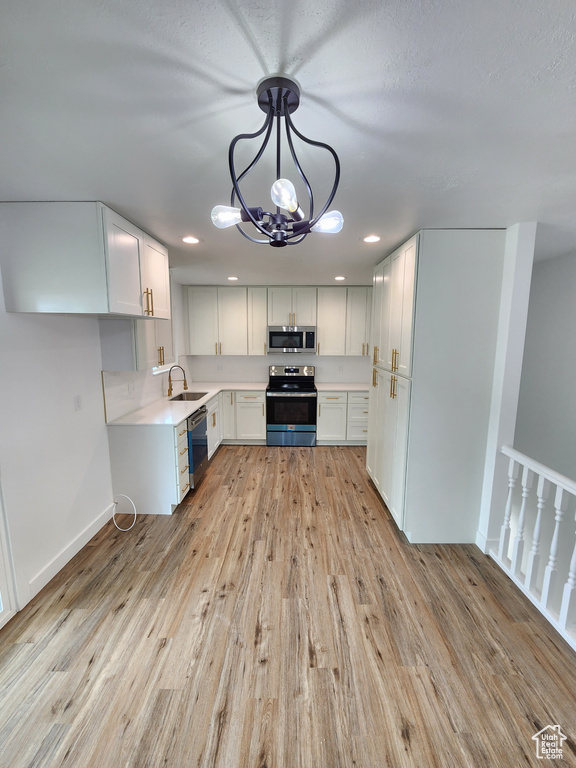 Kitchen with stainless steel appliances, light countertops, light wood-style floors, and a sink