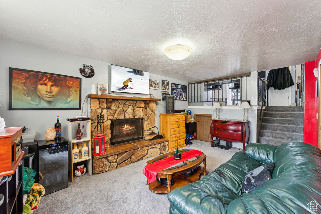 Carpeted living room with a fireplace, a textured ceiling, and stairs