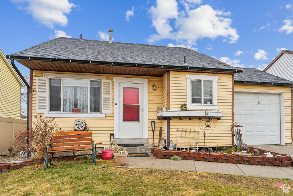 View of front of home with a garage, entry steps, a front yard, and roof with shingles