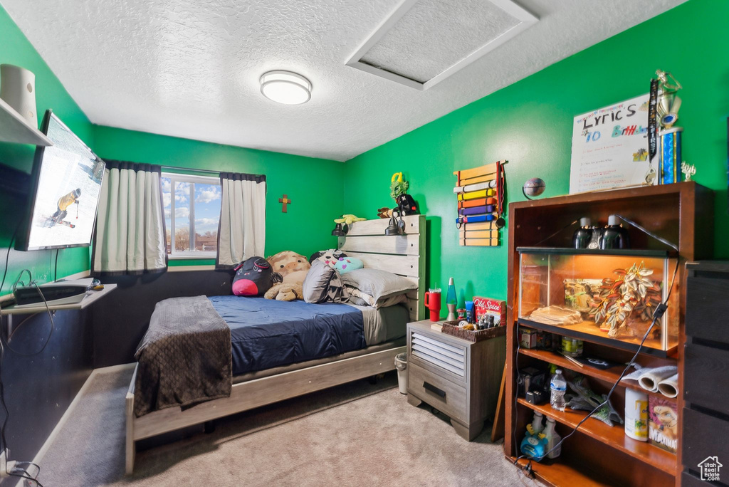 Carpeted bedroom featuring a textured ceiling and attic access