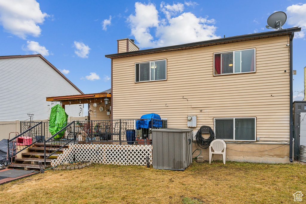 Back of property with a yard, a deck, and a chimney