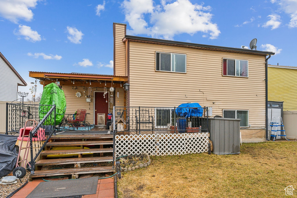 Back of property featuring a yard, a wooden deck, and a chimney