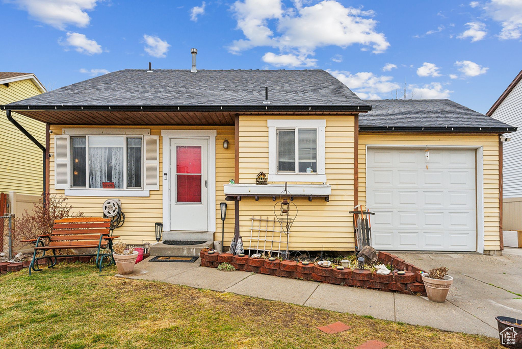 View of front of house featuring entry steps, concrete driveway, roof with shingles, and a front yard