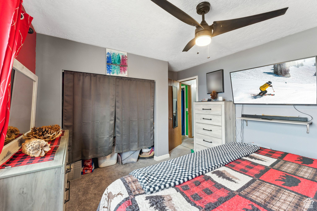 Carpeted bedroom featuring baseboards, a textured ceiling, and ceiling fan