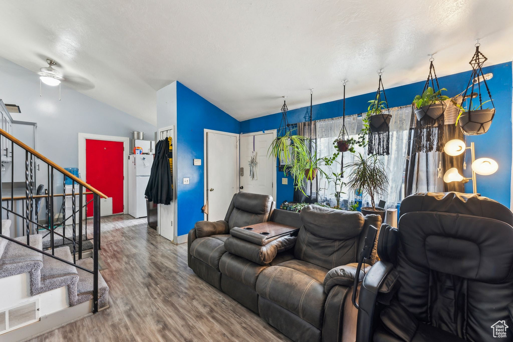 Living room with visible vents, stairway, vaulted ceiling, wood finished floors, and a ceiling fan