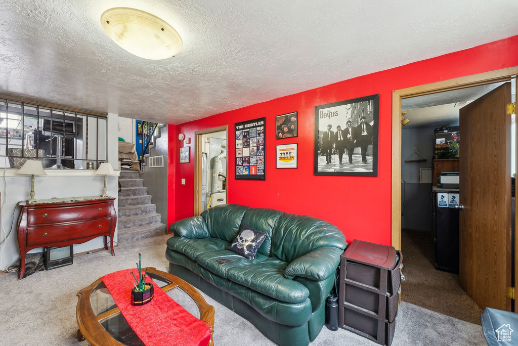 Carpeted living room featuring stairway and a textured ceiling